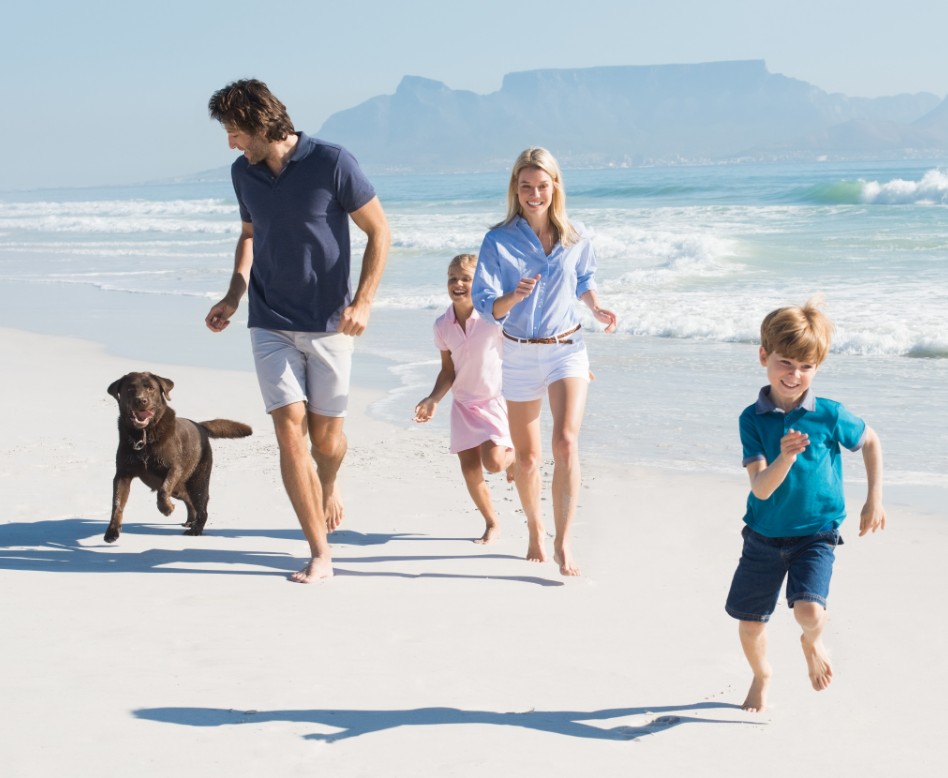 Whole family and their dog running along the beach.