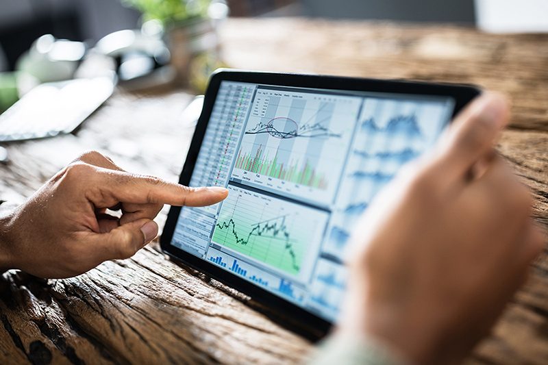 finger touching a tablet with stock graphs